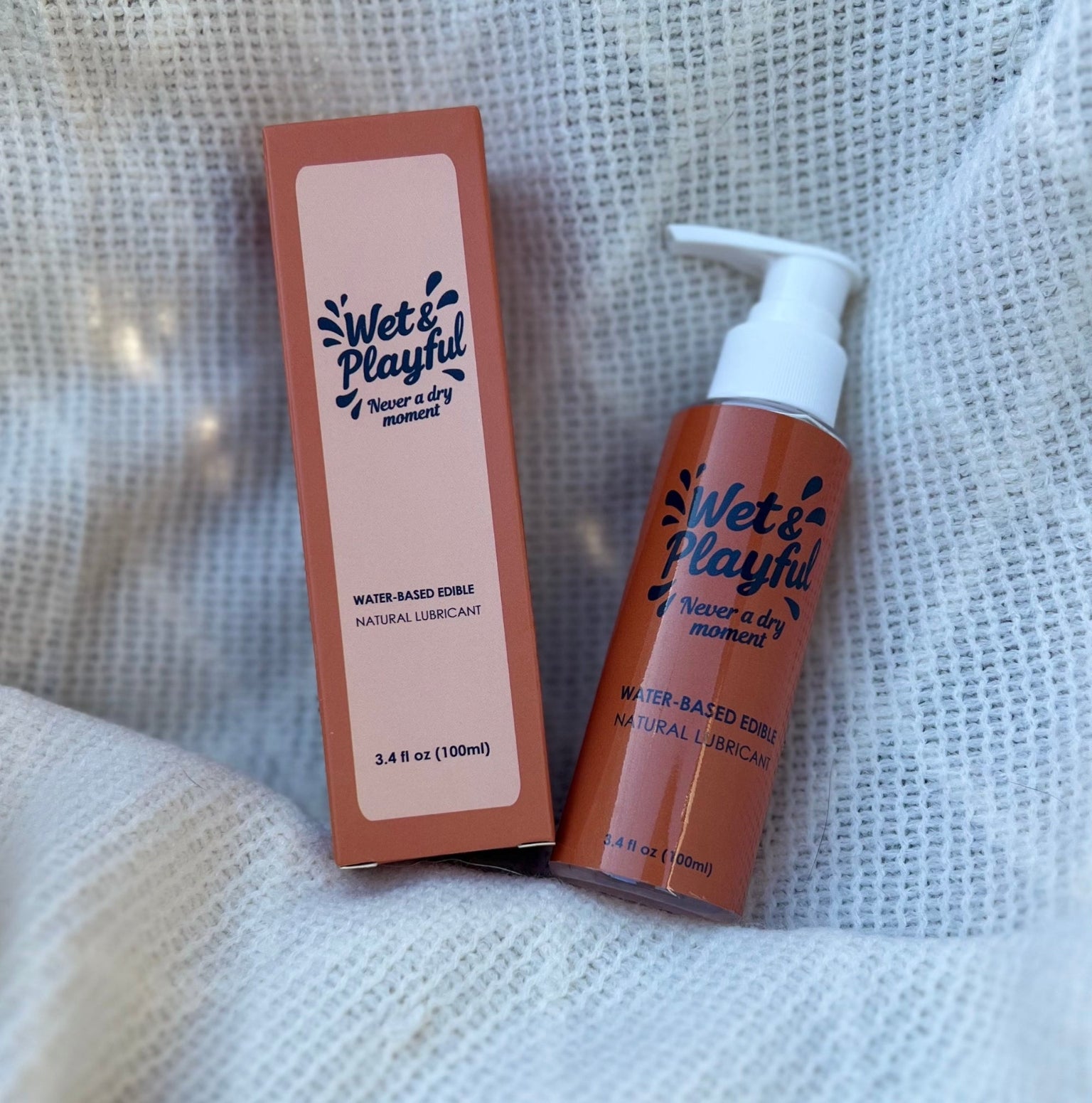 Wet & Playful water-based edible natural lubricant bottle and packaging on a textured white background